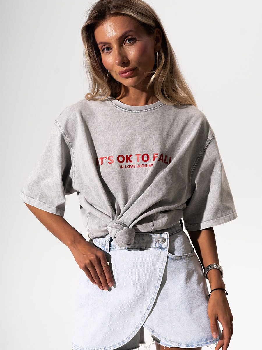 The t-shirt is in light gray color with the print It's OK to fall